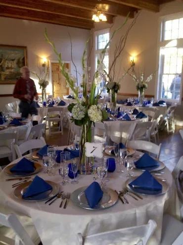 Reception dining room with blue napkins and tall floral arrangements