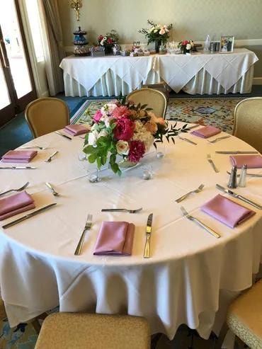 Round event table with pink napkins and floral centerpiece