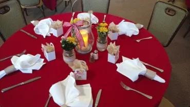 Round dining table with red linens and white napkins
