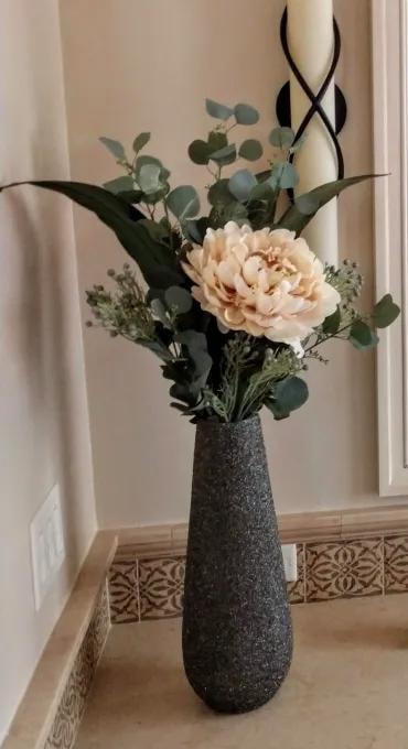 Tall dark vase with cream flowers and greenery